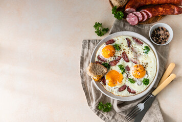 Fried eggs with sausage and parsley on a ceramic plate served with bread. Classic breakfast. Top view.