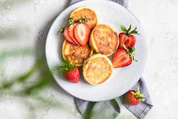 Cottage cheese pancakes or fritters with strawberry and natural yogurt. Healthy breakfast or lunch. Syrniki.