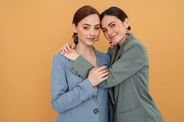 Young two women wearing jackets hugging and smiling at camera