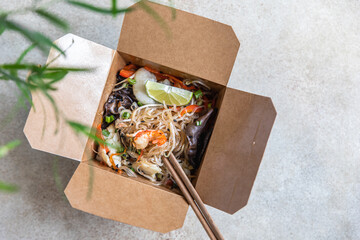 Asian glass noodles with different types of seafood, vegetables and shiitake mushroom in disposable box. Traditional Asian takeaway food. Top view.