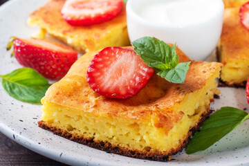 Cottage cheese casserole with strawberries and mint. Delicious homemade dessert made of curd and fresh berries with cream. close up