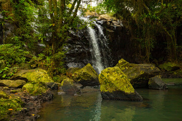 Waterfall landscape. Beautiful hidden waterfall in tropical rainforest. Foreground with big stones. Fast shutter speed. Sing Sing Angin waterfall, Bali, Indonesia