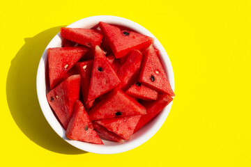 Watermelon slices on white bowl on yellow background. Top view