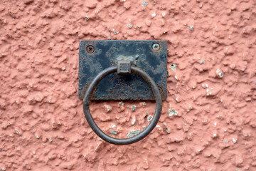 Detail of Black Iron Ring Mounted on Rough Textured Pink Wall