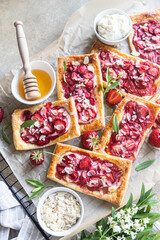Delicious sweet sliced pies with strawberry. Puff pastry mini pies with strawberry, cream cheese, almond and honey. Top view.