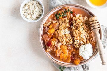 Ceramic plate with tasty plum crumble dessert served with vanilla ice cream and herbs. Top view.