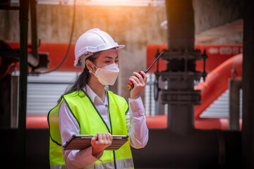 Engineer checking blueprint of industry cooling tower air conditioner is water cooling tower air chiller HVAC of large industrial building to control air system ,wearing mask for protect pollution.