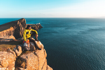 Man sitting on top of a cliff in Scotland