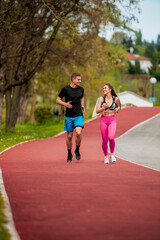 Young sportive couple in sporty outfit doing some exercise together at a park