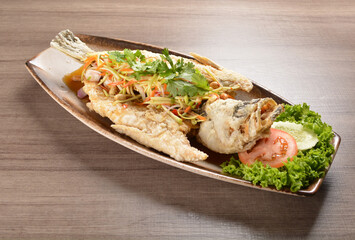 deep fried crispy whole grouper fish with mango salad dressing on wood background asian halal menu