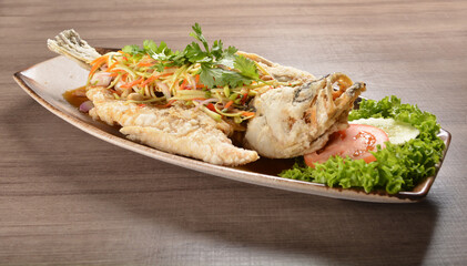 deep fried crispy whole grouper fish with mango salad dressing on wood background asian halal menu