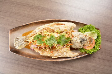 deep fried crispy whole grouper fish with mango salad dressing on wood background asian halal menu