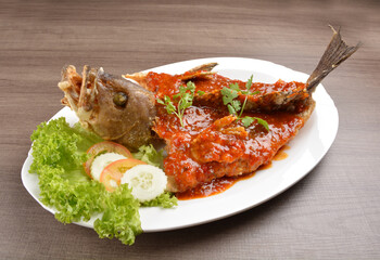 deep fried crispy whole grouper fish with spicy sambal chilli sauce on wood background asian halal menu