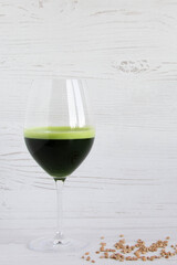 Detox wheatgrass juice in a glass shot and wheat grains on a wooden background. wellness shots. healthy shot. Nutrition food. green superfood drink
