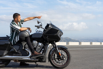 Fototapeta na wymiar Chico señalando el camino sentado en una moto.