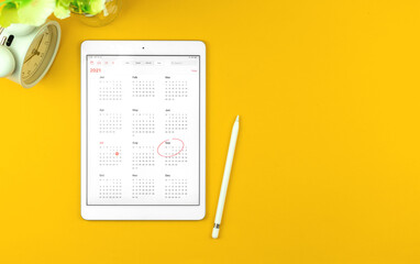 Tablet with September month 2021 calendar, yellow desktop background with copy space, top view photo