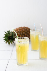 Delicious sweet refreshing pineapple juice with ice in glasses with a straw