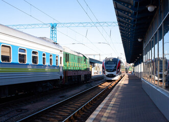 Fototapeta premium Modern high-speed train moves fast along the platform. Train arrive. The train arrives at the train station. Old passenger trains standing.