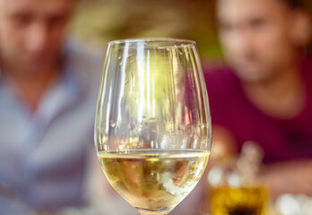 Glass on a high thin leg with white wine in a restaurant