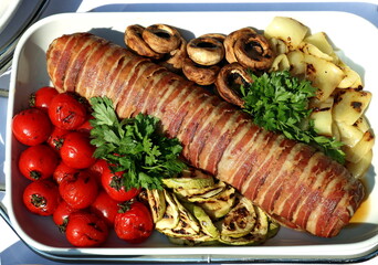 Rolled beefsteak with a side dish of mushrooms, tomatoes, zucchini and potatoes served in  a Serbian restaurant