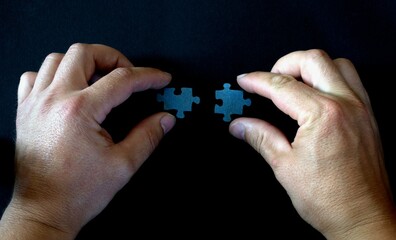 A person's hands connect two elements of the puzzle.