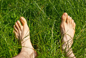 Barefoot male feet on the green grass. Bare feet close up.