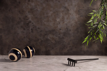 Closeup of a mini wooden rake with striped balls on the white marble surface.