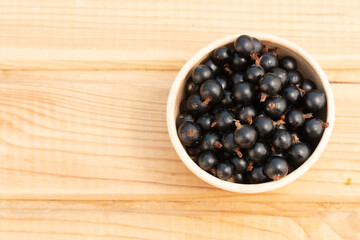 black currant berries in a clay plate. black currant on a wooden table