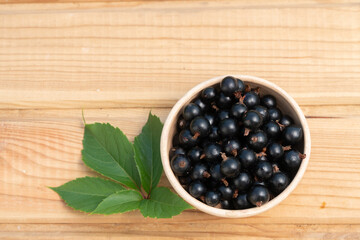 black currant berries in a clay plate. black currant on a wooden table