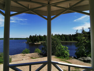 View from the Tea gazebo on the picturesque shore of the Vyborg Bay in the Monrepos Park of the city of Vyborg against the background of a blue sky with clouds.