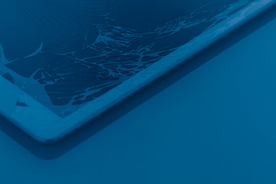 cracked or broken screen of smartphone or tablet on plain background, blue light at night effect, diagonal line of photography composition