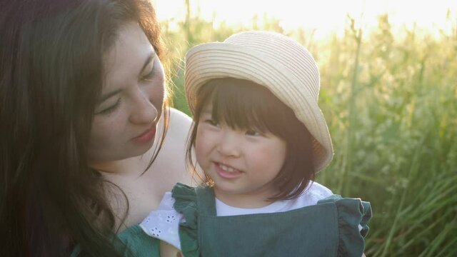 koreans family mother and daughter in green dresses sitting in the long grass