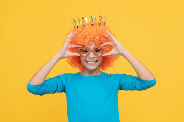 cheerful selfish child girl in curly wig and princess diadem wear party glasses, birthday