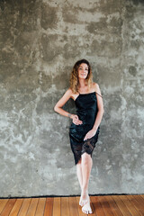 Fototapeta na wymiar portrait of a beautiful woman in a black dress on a gray background
