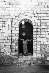 a young woman stands with her back on the ruins of an ancient fortress, black and white photography