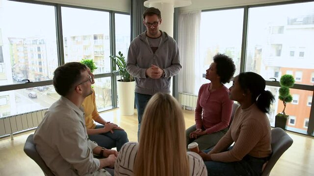 Diverse group of people sitting in circle in group therapy session.