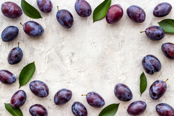 Purple plums with leaves top view. Food fruits background