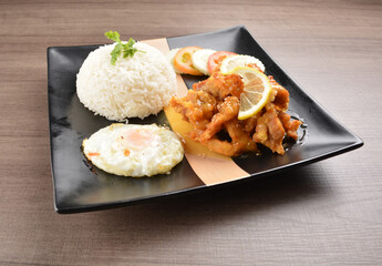 stir fried chicken meat in lemon sour sauce with white rice and fried egg on wood background asian halal set lunch menu