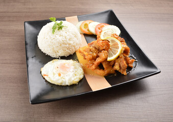 stir fried chicken meat in lemon sour sauce with white rice and fried egg on wood background asian halal set lunch menu