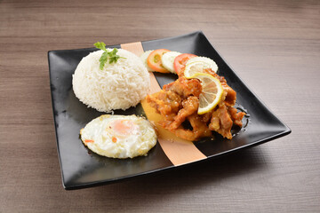 stir fried chicken meat in lemon sour sauce with white rice and fried egg on wood background asian halal set lunch menu