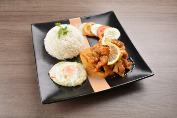 stir fried chicken meat in lemon sour sauce with white rice and fried egg on wood background asian halal set lunch menu