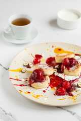 Cheesecakes with berry and mango sauce, chocolate, cherry