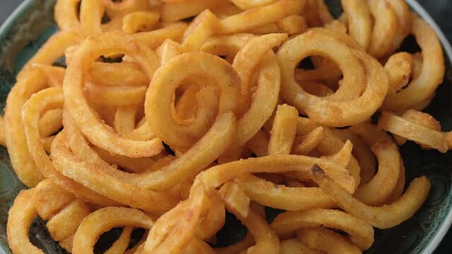 Golden Spicy Seasoned Curly Fries ready to eat. rotating video