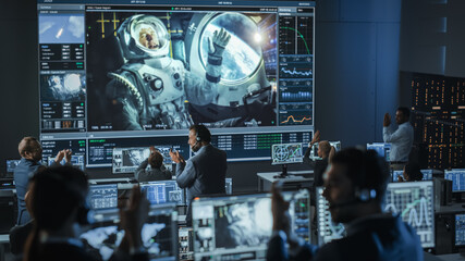 Group of People in Mission Control Center Establish Successful Video Connection on a Big Screen...