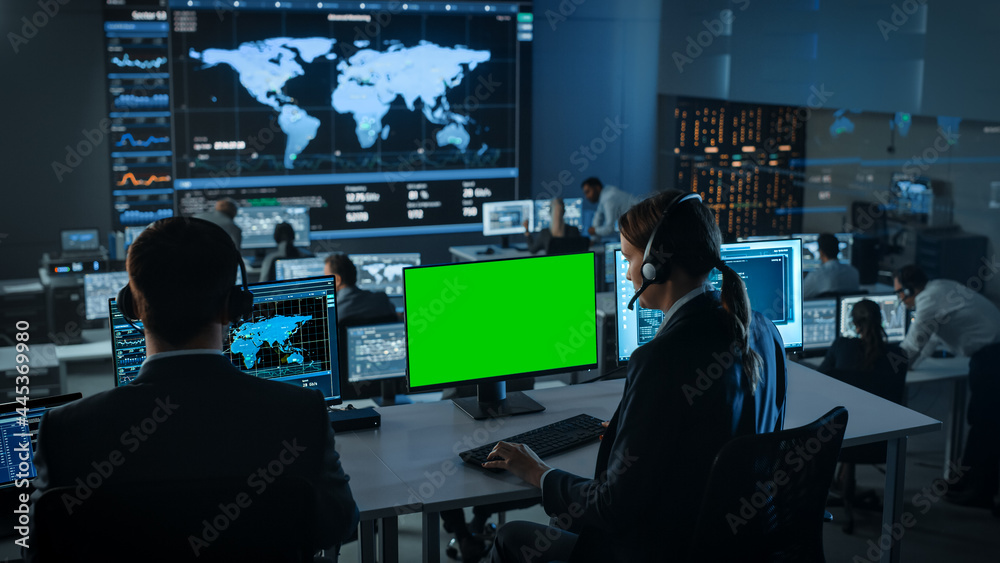 Aufkleber Green Screen Horizontal Mock Up on Computer Display Used by a Female Client Support Specialist Wearing Headset. Team of Engineers Work in Control and Monitoring Room with Displays with Big Data.
