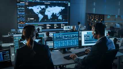 Shot of Officers in a Surveillance Control Center with Police Global Map Tracking on a Big Digital...