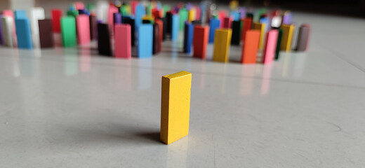 Isolated yellow wooden block on a background of colorful dominos