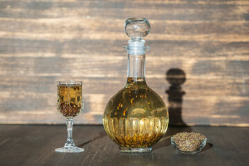 Obraz na płótnie Canvas Homemade birch buds tincture in a glass bottle and a wine crystal glass on a wooden table background