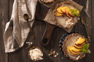 Nectarine vegan tarts with grated coconut and crunchy peanuts. Date, walnut, almond and hazelnut base.