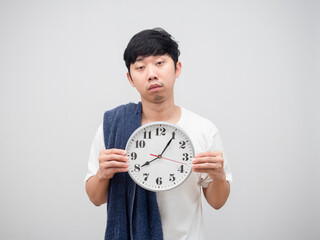 Asian man with towel holding clock sleepy face on white background